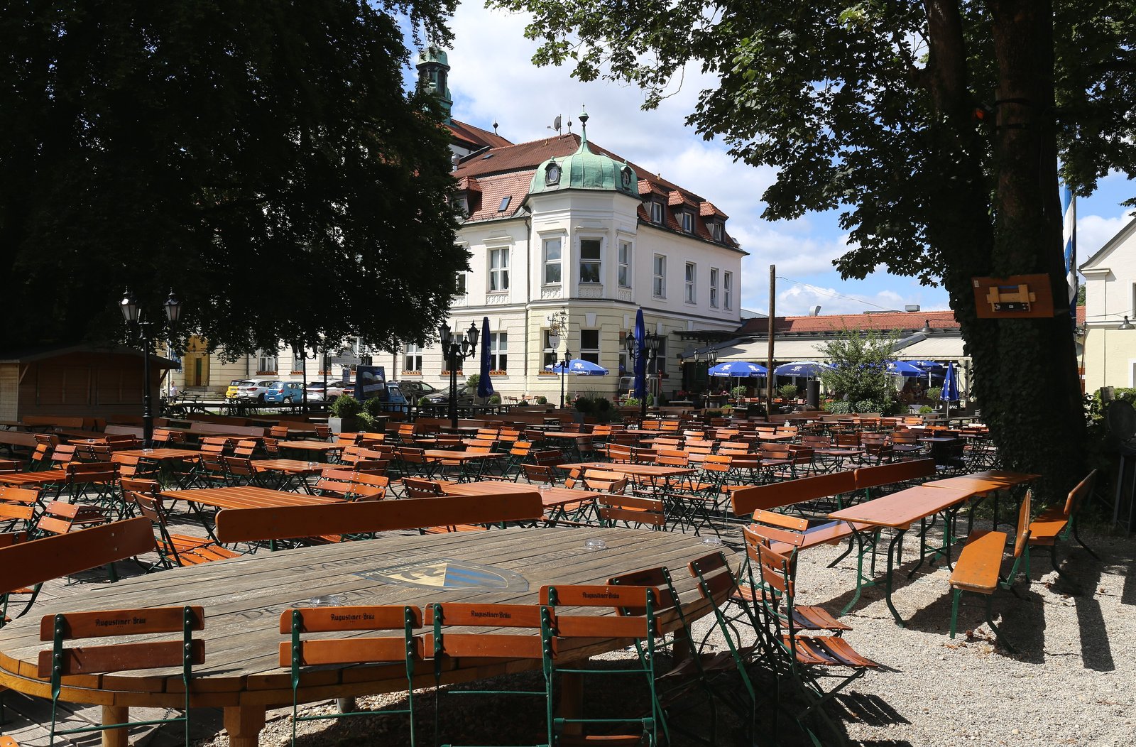 Rows of wooden tables and benches under chestnut trees in a Bavarian beer garden