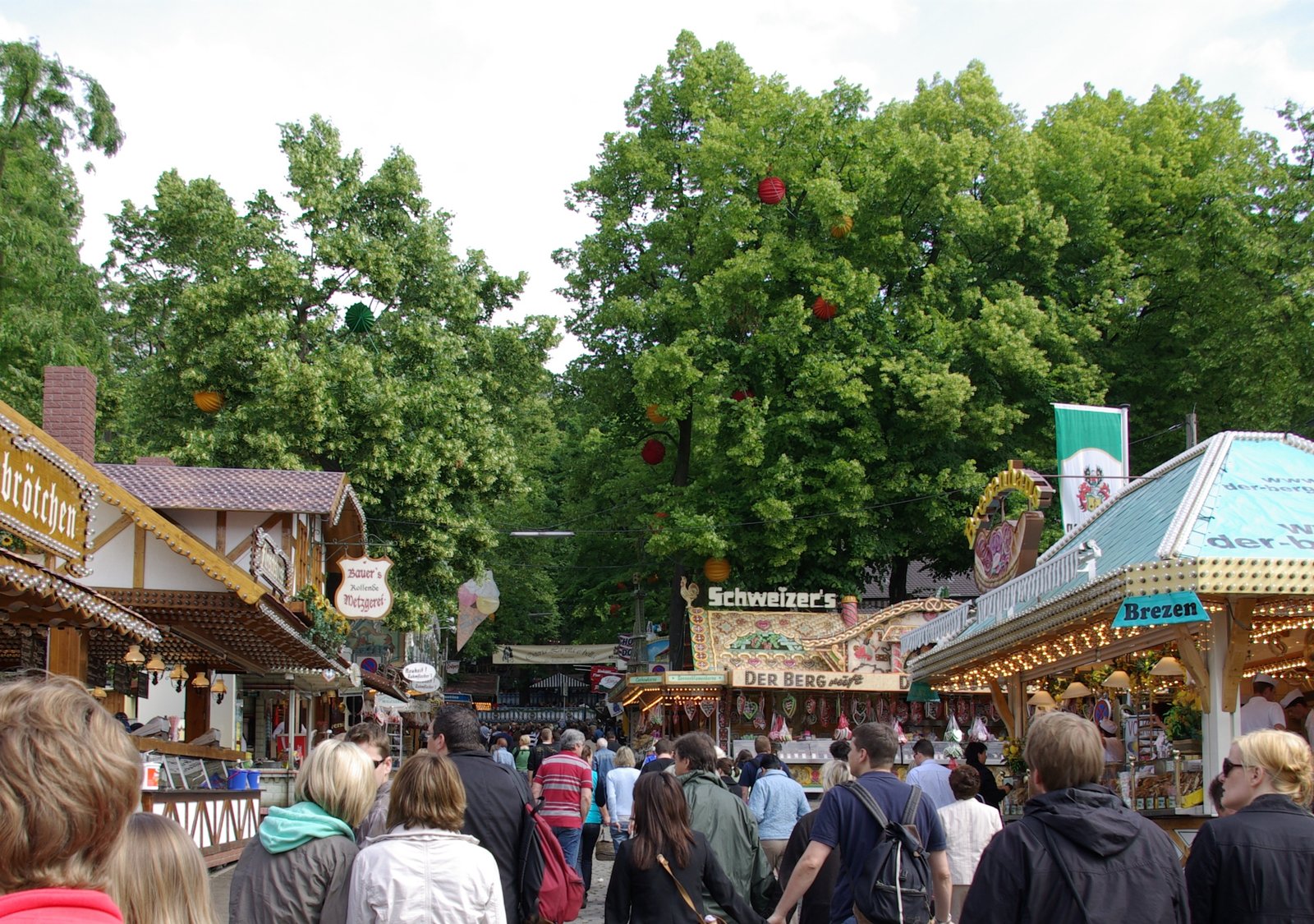 Fairground stalls and crowds under big trees at the Erlanger Bergkirchweih