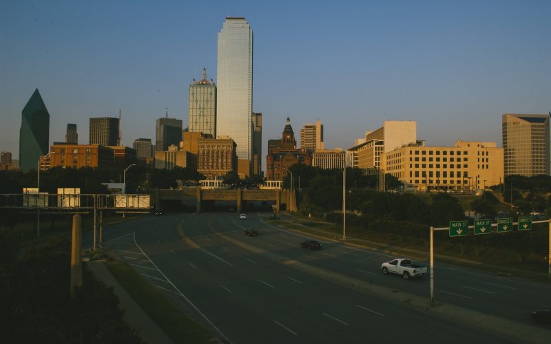 Dallas towers lit by evening sun above a downtown highway