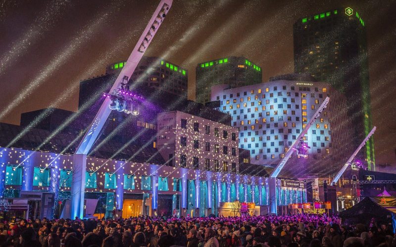 Illuminated stage and light beams over a crowd at Montréal en Lumière at night