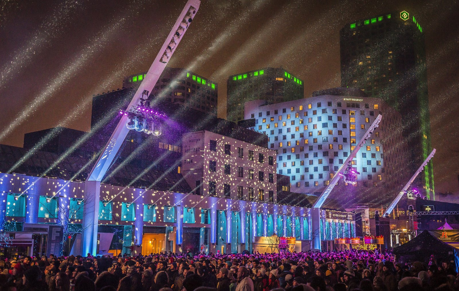 Illuminated stage and light beams over a crowd at Montréal en Lumière at night