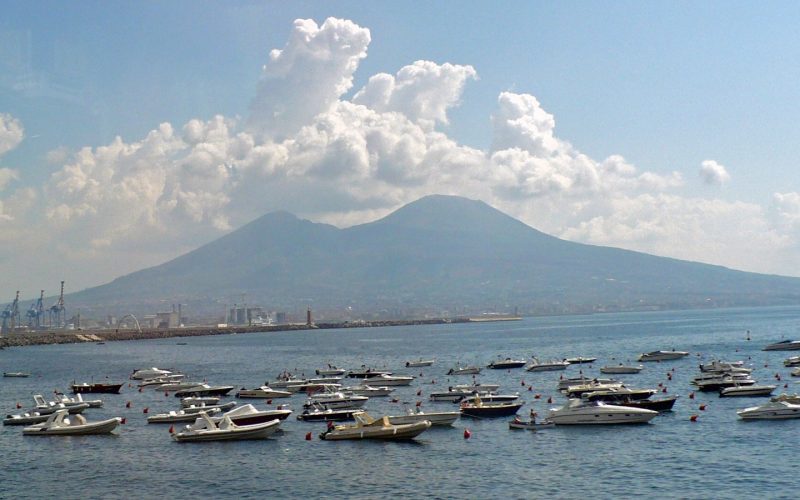 Mount Vesuvius beneath towering clouds above boats in the Bay of Naples