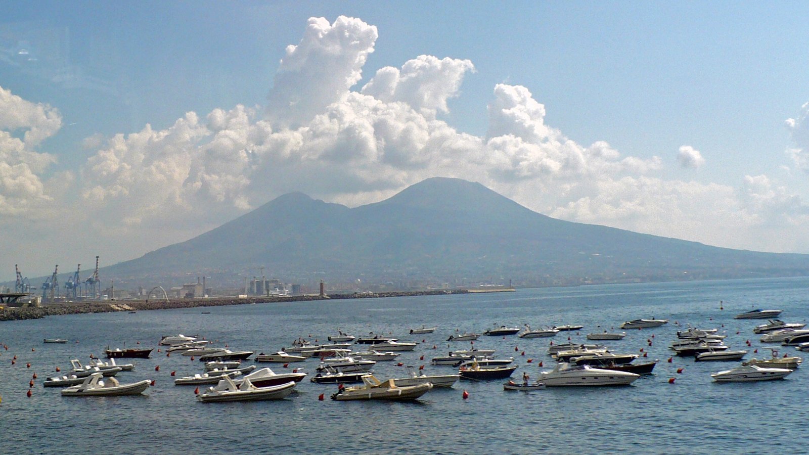 Mount Vesuvius beneath towering clouds above boats in the Bay of Naples