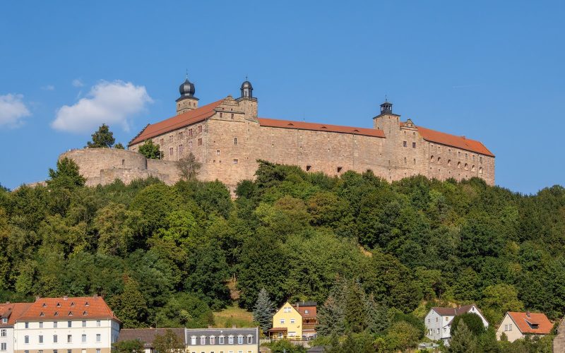 Plassenburg fortress above the rooftops of Kulmbach under a blue sky