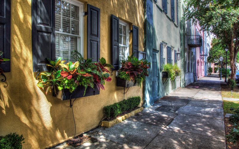 Sunlit pastel houses with flower boxes along Rainbow Row in Charleston