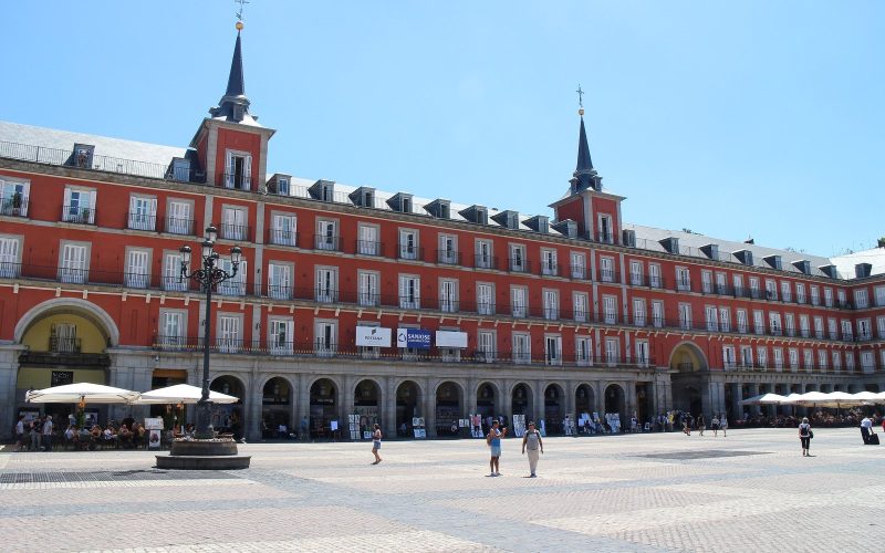 Plaza Mayor in Madrid with its red-fronted arcades under a clear sky