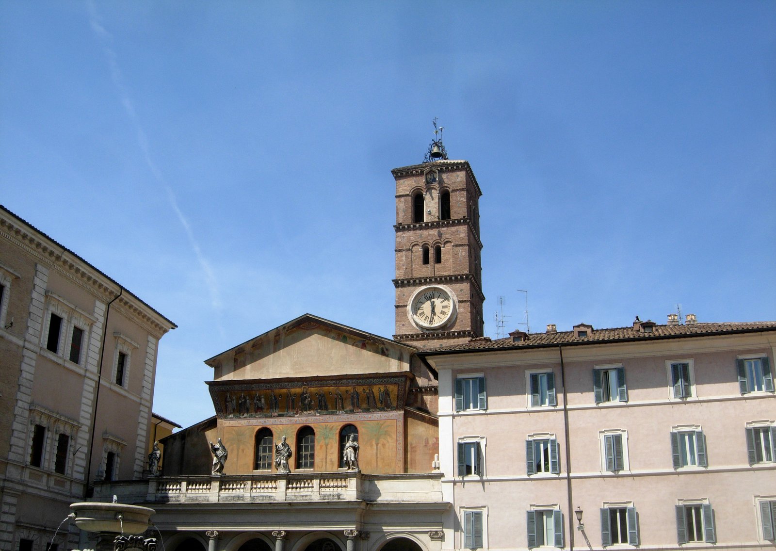 Santa Maria in Trastevere bell tower and ochre facades under a deep blue sky in Rome