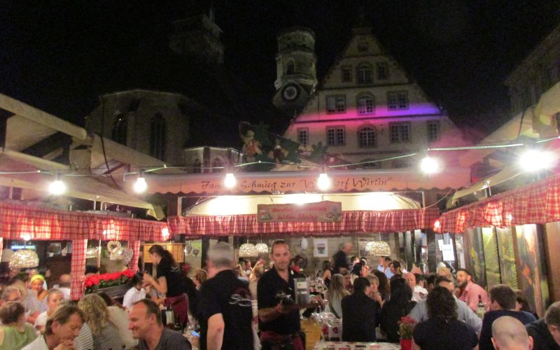 Lit wine stalls and crowd on the square at the Stuttgarter Weindorf at night