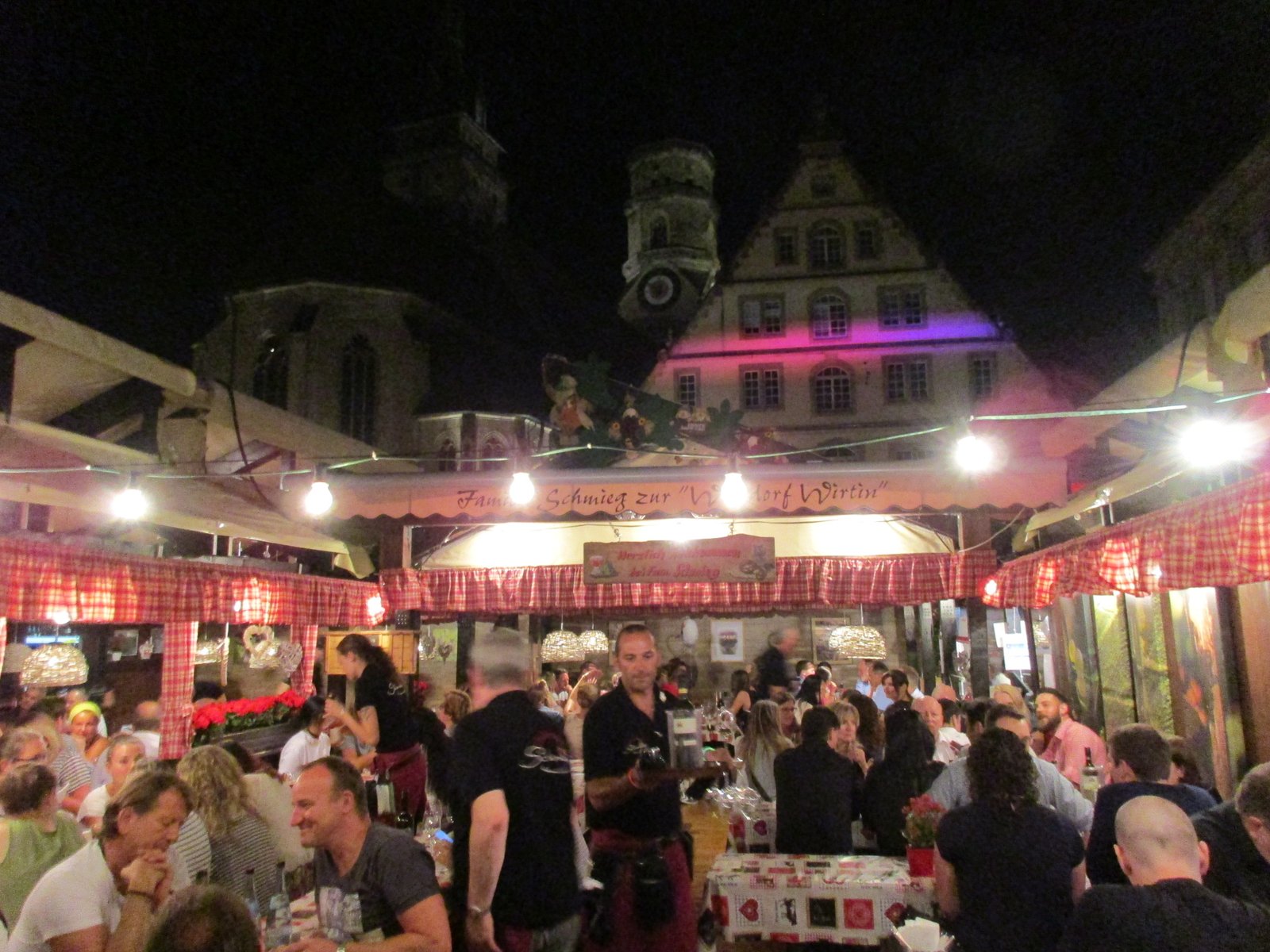 Lit wine stalls and crowd on the square at the Stuttgarter Weindorf at night