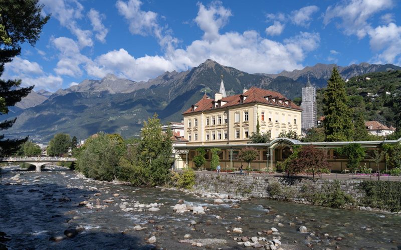 The Passer river and a historic building below snow-dusted mountains in Merano