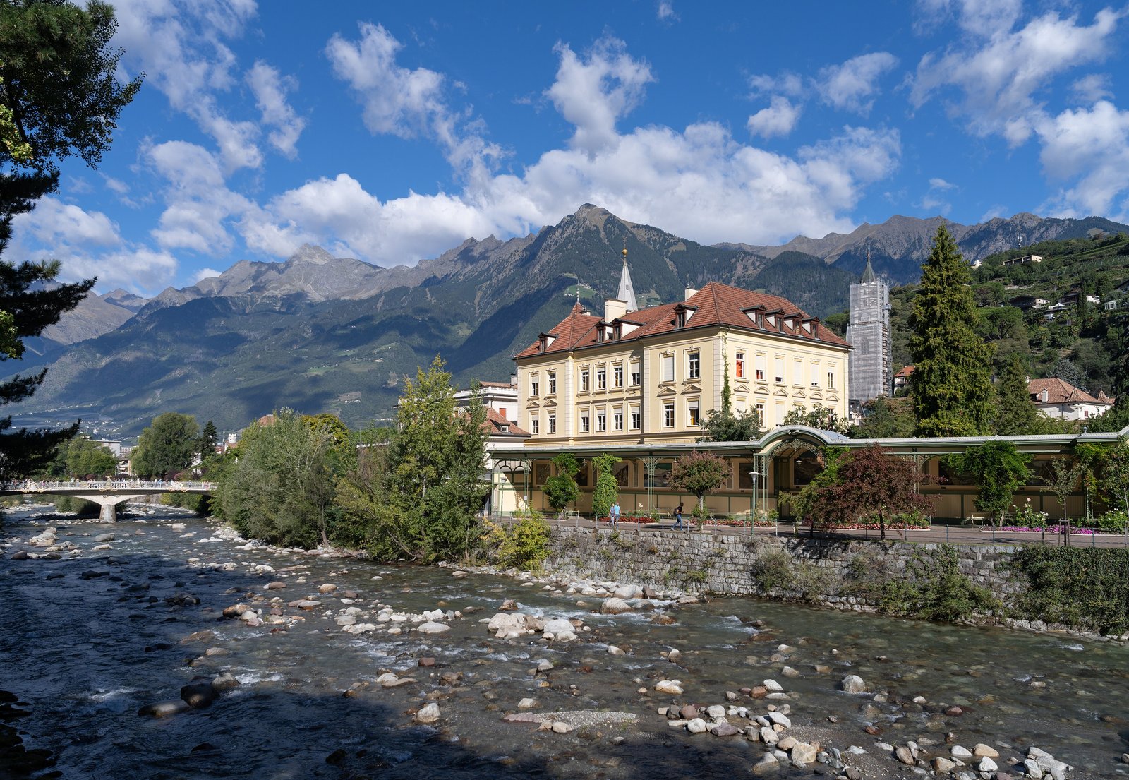 The Passer river and a historic building below snow-dusted mountains in Merano