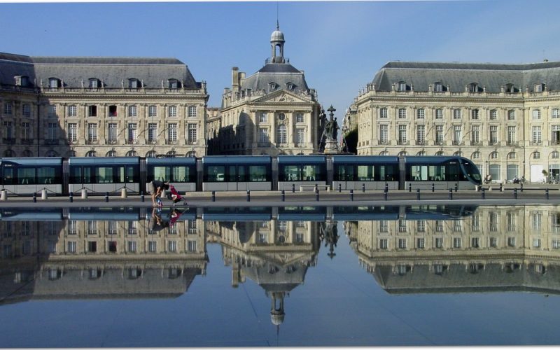 Place de la Bourse in Bordeaux mirrored in the Miroir d'eau with a tram passing