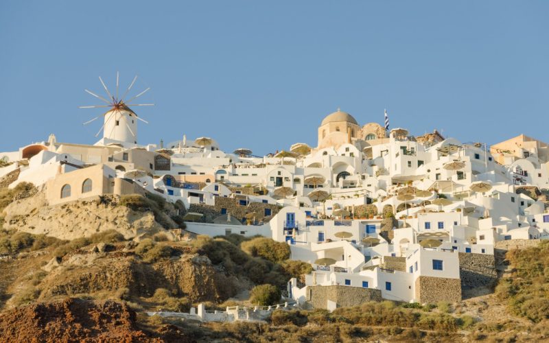White houses and a windmill on the cliff of Oia on Santorini under a clear sky