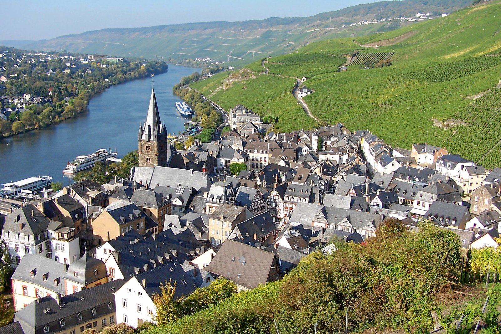 Bernkastel-Kues roofs and church tower beside the Moselle with steep vineyards behind