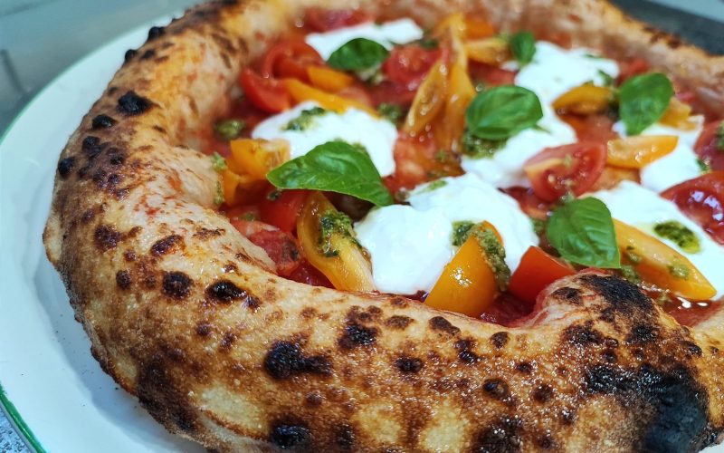 Neapolitan pizza with charred crust, tomatoes and buffalo mozzarella
