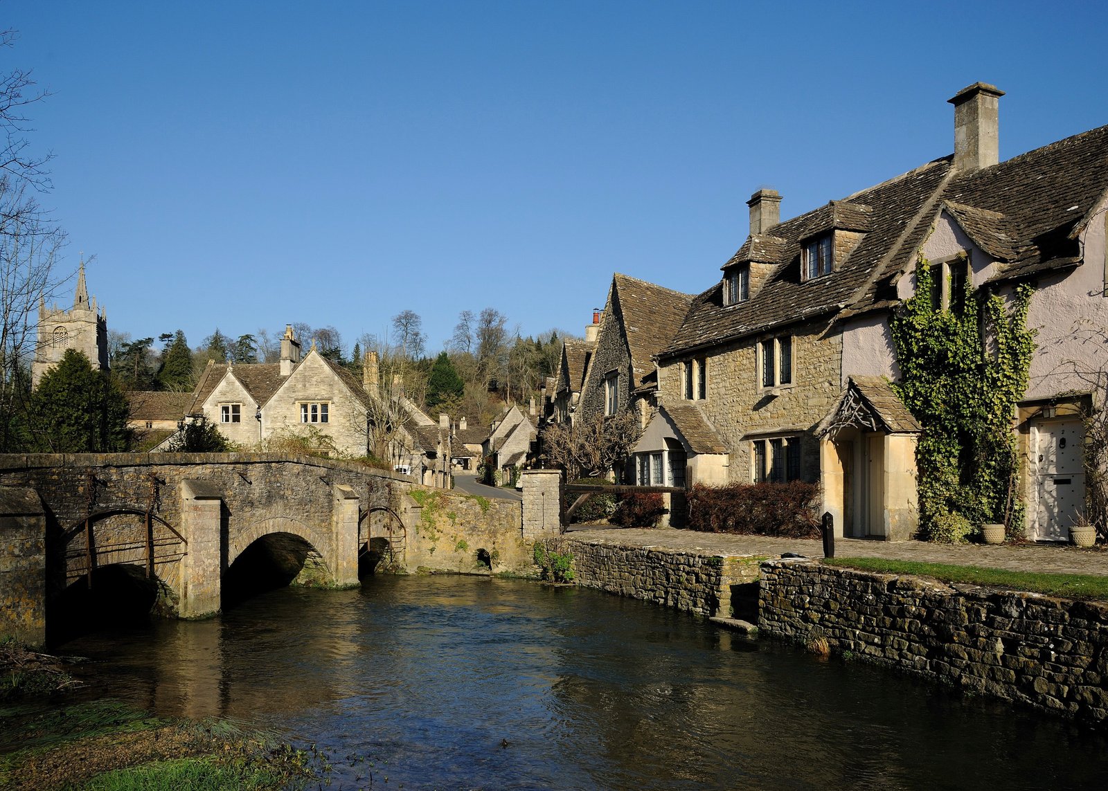 Stone bridge and honey-coloured cottages beside the river at Castle Combe