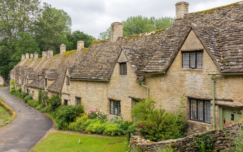 Row of honey-stone cottages along a lane in Bibury, the Cotswolds
