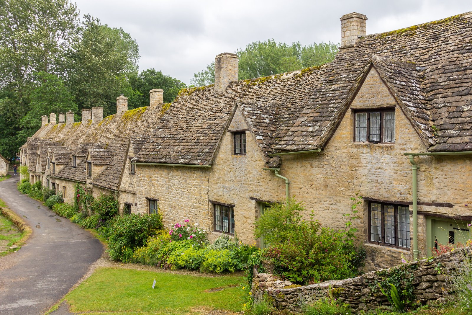 Row of honey-stone cottages along a lane in Bibury, the Cotswolds