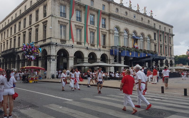 Revellers in white and red walking past the Bayonne town hall during the Fêtes de Bayonne