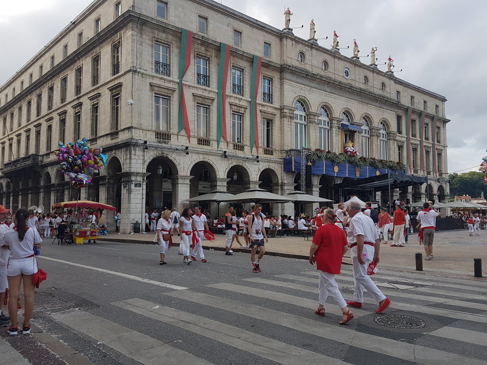 Revellers in white and red walking past the Bayonne town hall during the Fêtes de Bayonne