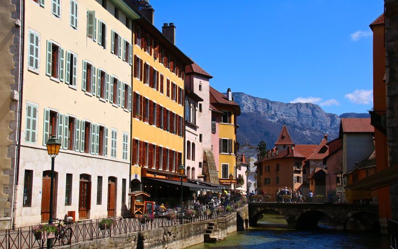 Canal lined with colourful houses in old Annecy with the Alps behind