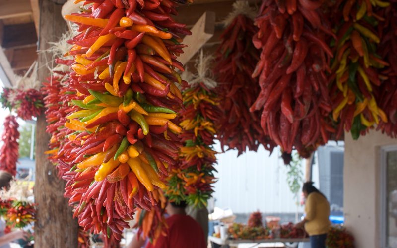 Bunches of red and orange chile ristras hanging at a New Mexico market