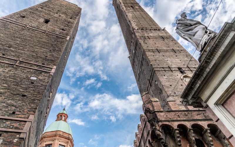 The Asinelli and Garisenda towers of Bologna rising against a blue sky with clouds
