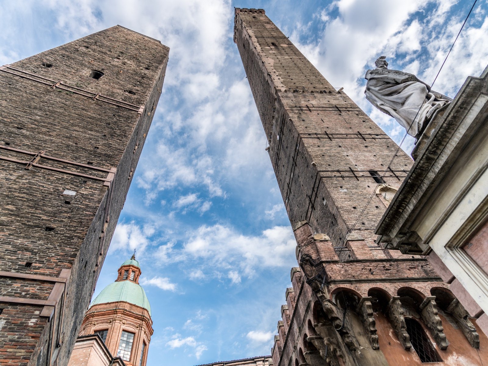 The Asinelli and Garisenda towers of Bologna rising against a blue sky with clouds