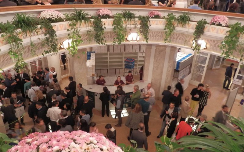 Visitors tasting wine in the flower-decked atrium of the Kurhaus during Merano WineFestival