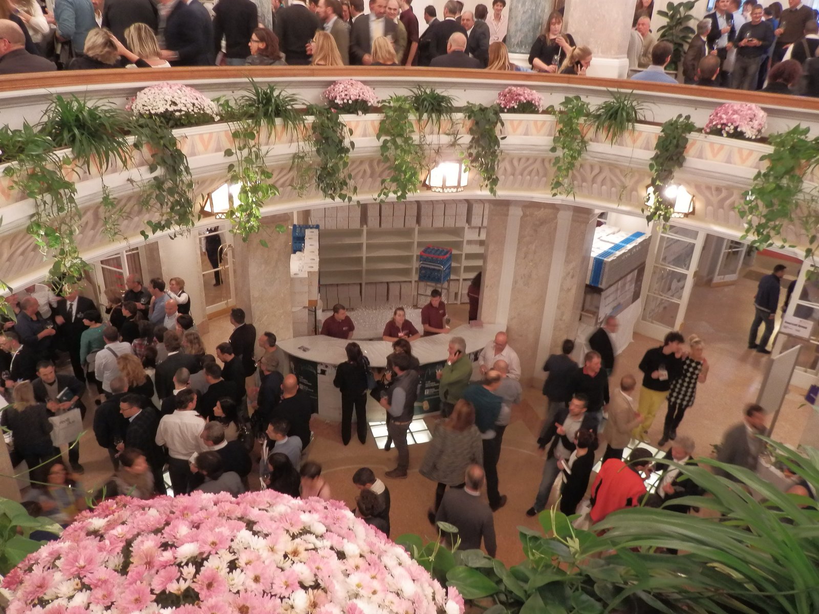 Visitors tasting wine in the flower-decked atrium of the Kurhaus during Merano WineFestival
