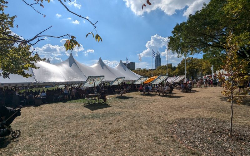White festival tents on the Cincinnati riverfront with the downtown skyline behind