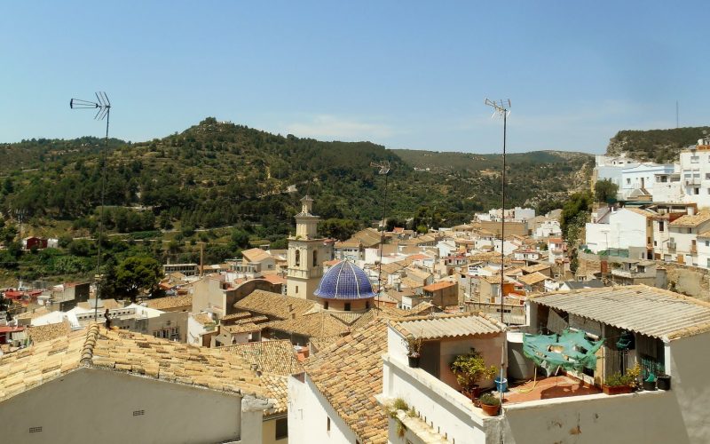 Rooftops and blue-domed church of Buñol among wooded hills