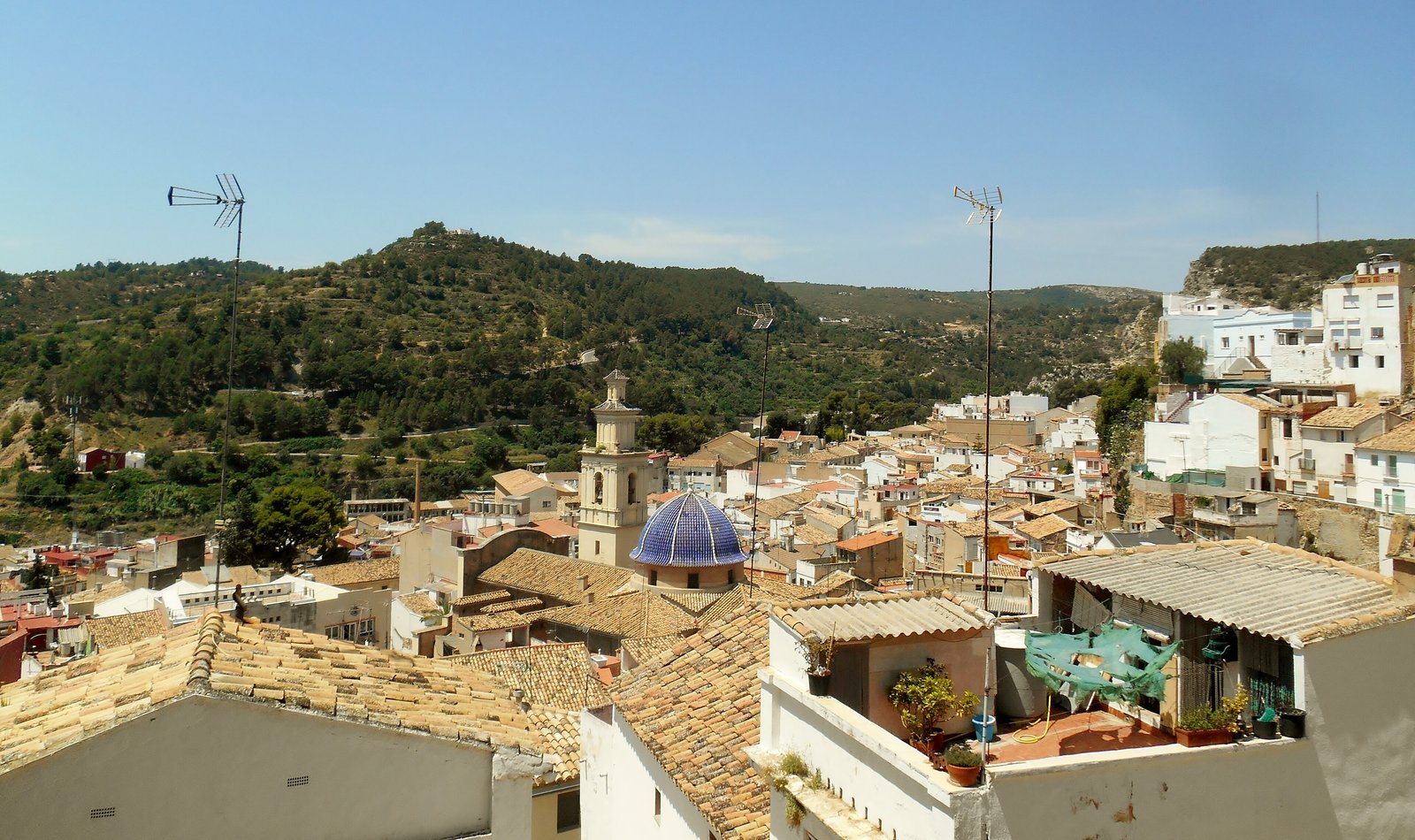 Rooftops and blue-domed church of Buñol among wooded hills