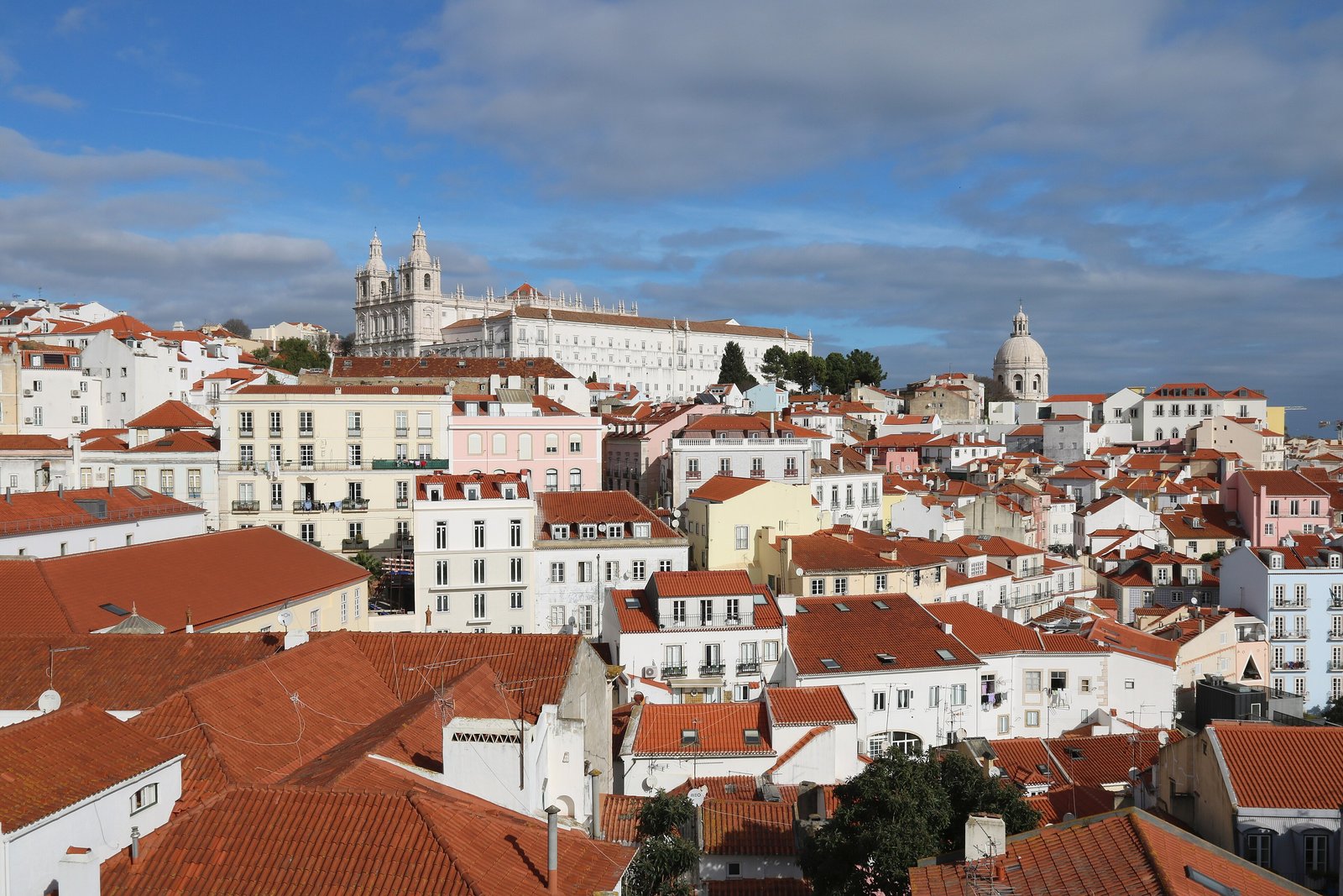Terracotta rooftops of Alfama in Lisbon with the Tagus beyond