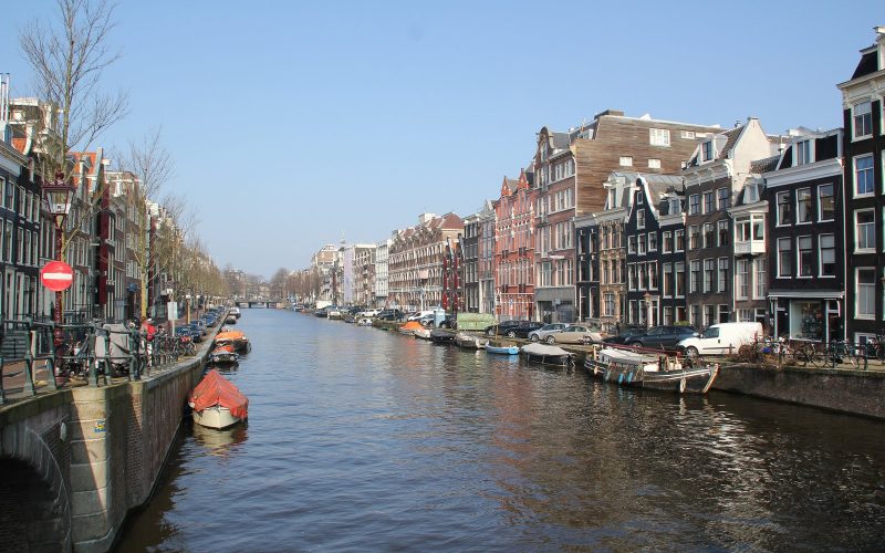 Amsterdam canal lined with gabled houses and moored boats
