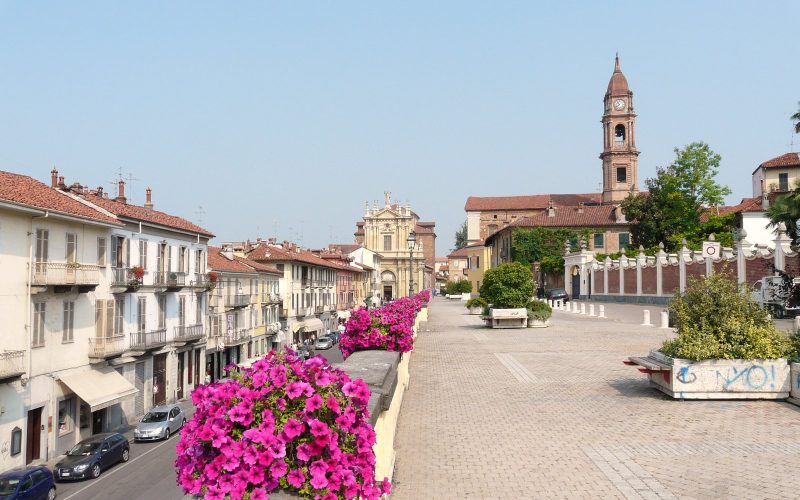 Wide pedestrian avenue lined with flowers and church towers in the town of Bra