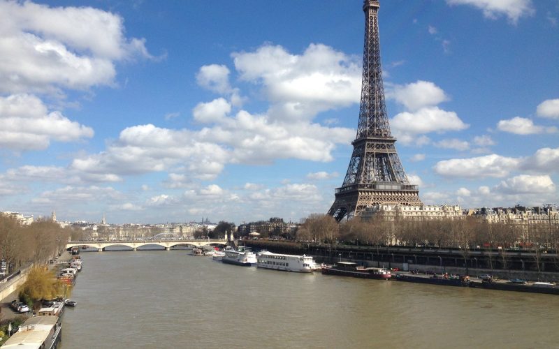 The Eiffel Tower rising above the Seine in Paris under a blue sky