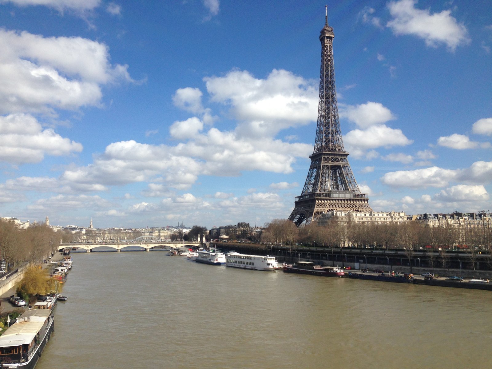 The Eiffel Tower rising above the Seine in Paris under a blue sky