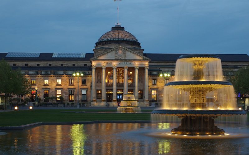 The Wiesbaden Kurhaus lit at dusk with its illuminated fountain