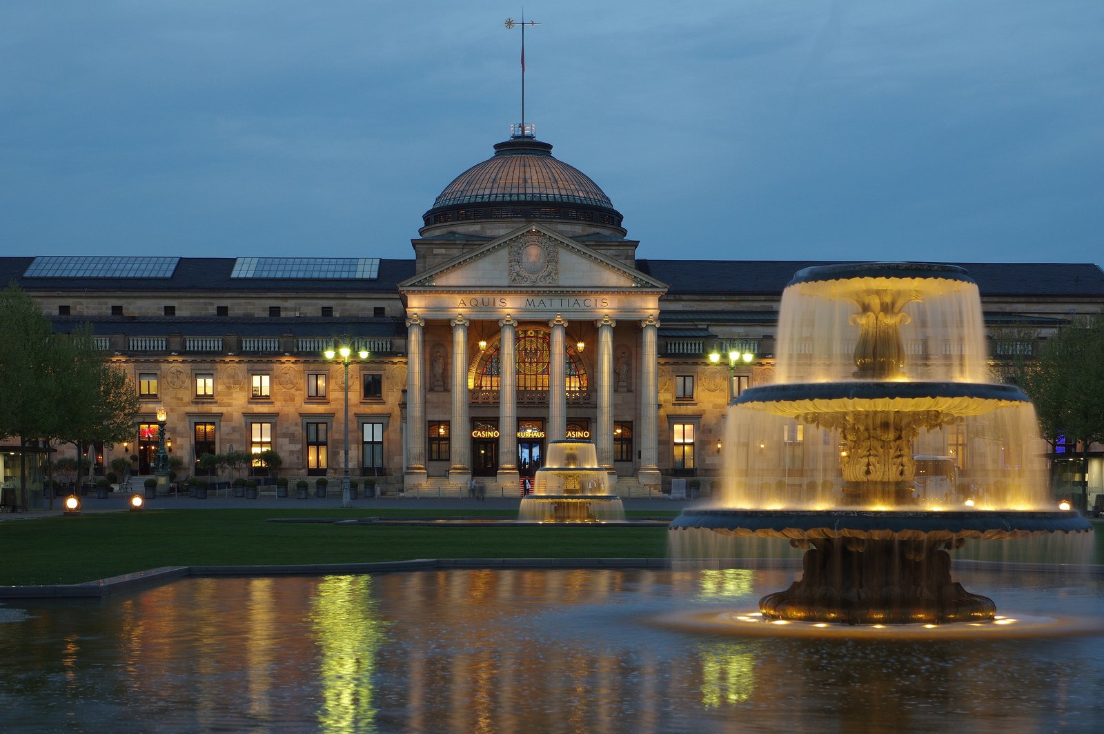 The Wiesbaden Kurhaus lit at dusk with its illuminated fountain