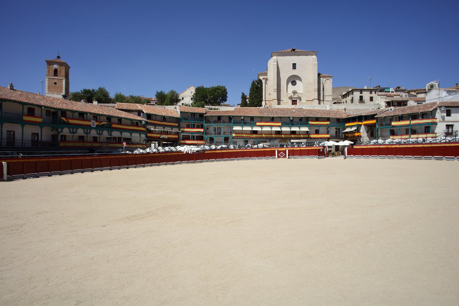 Arcaded Plaza Mayor of Chinchón with green balconies under a blue sky