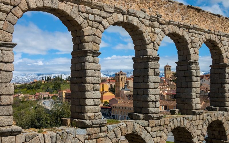 Roman aqueduct arches framing the red roofs of Segovia in Spain