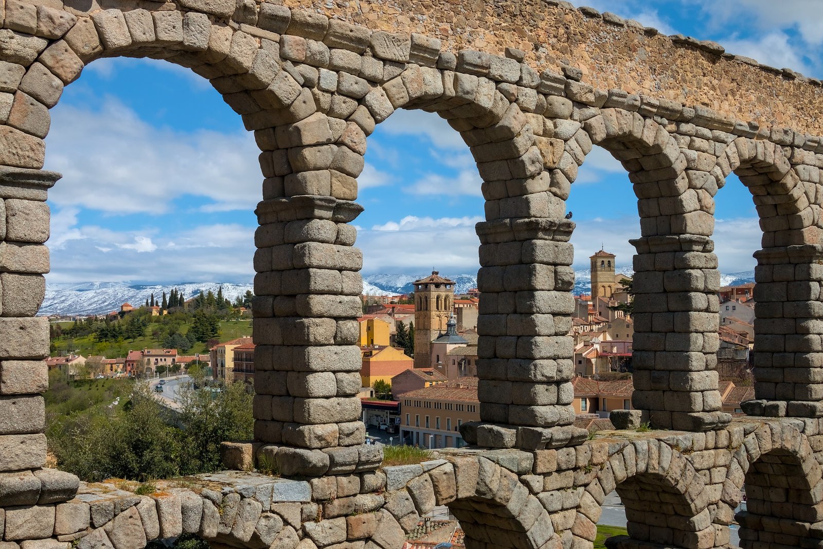 Roman aqueduct arches framing the red roofs of Segovia in Spain