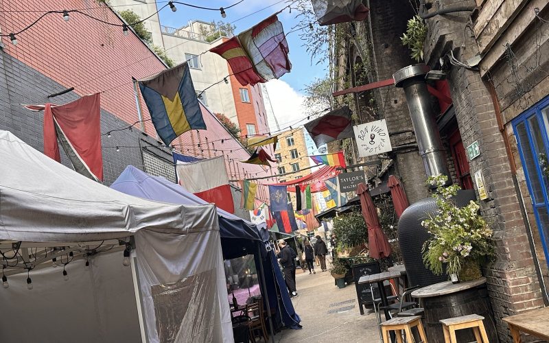 Market stalls and bunting in the Ropewalk alley of Maltby Street Market in Bermondsey, London