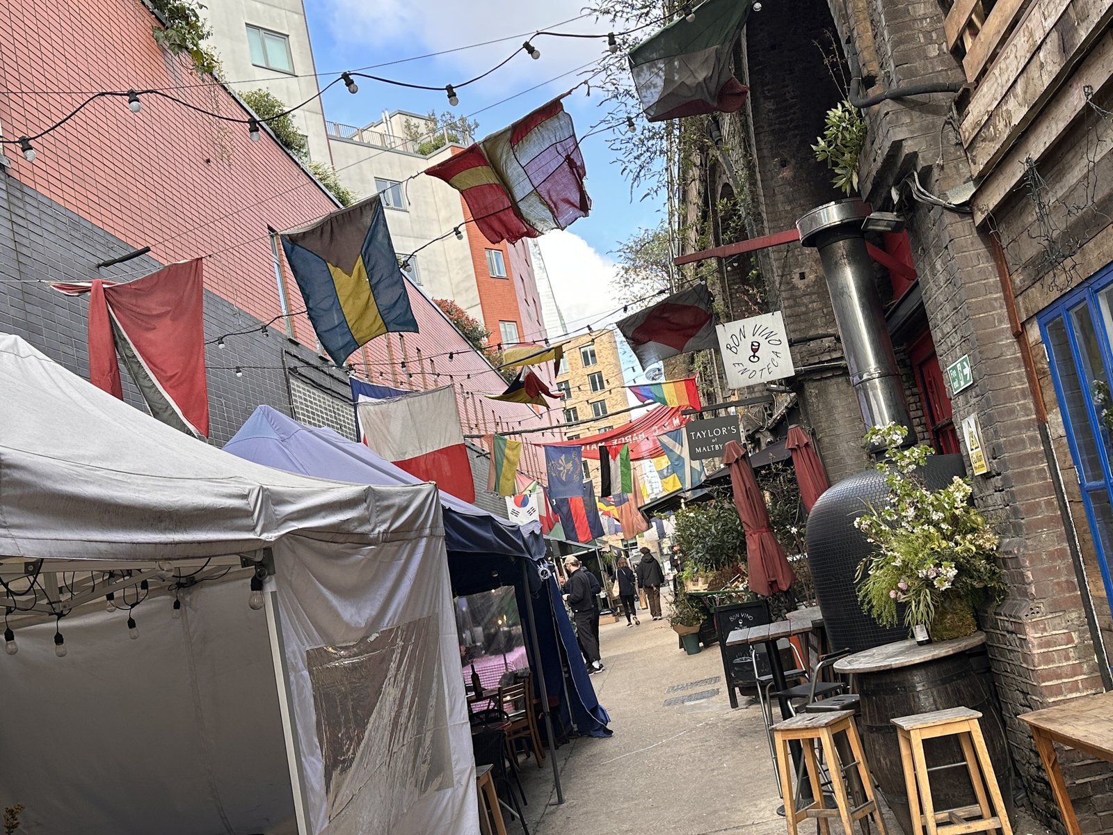 Market stalls and bunting in the Ropewalk alley of Maltby Street Market in Bermondsey, London