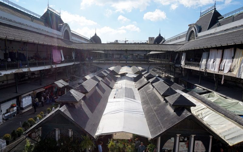 Courtyard of the Mercado do Bolhão with fruit and flower stalls under a blue sky in Porto