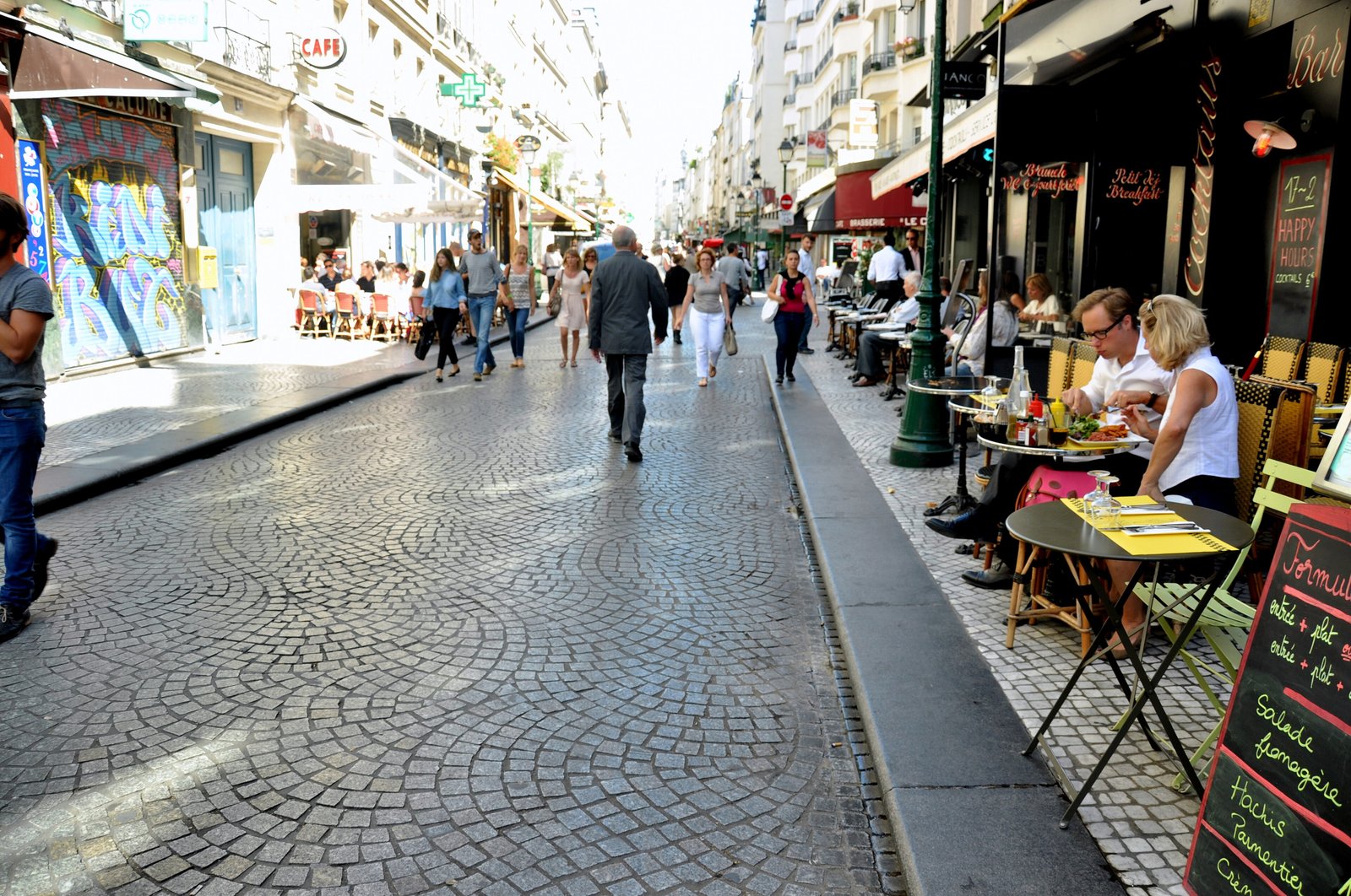 Cobbled pedestrian rue Montorgueil lined with café terraces and food shops in Paris