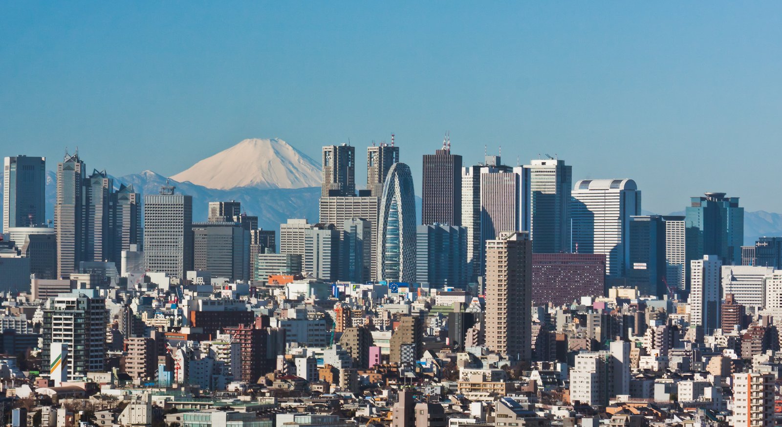Shinjuku skyscrapers in Tokyo with snow-capped Mount Fuji behind