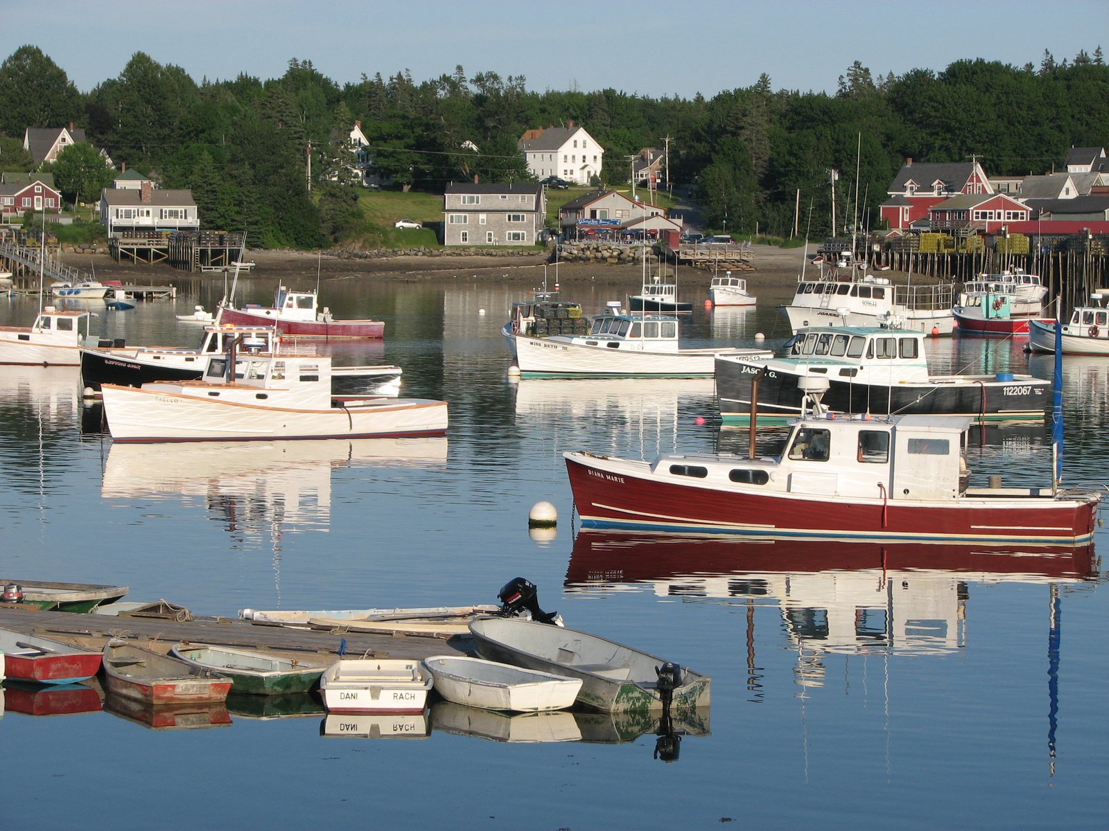 Lobster boats moored in a calm Maine harbor with waterfront houses behind